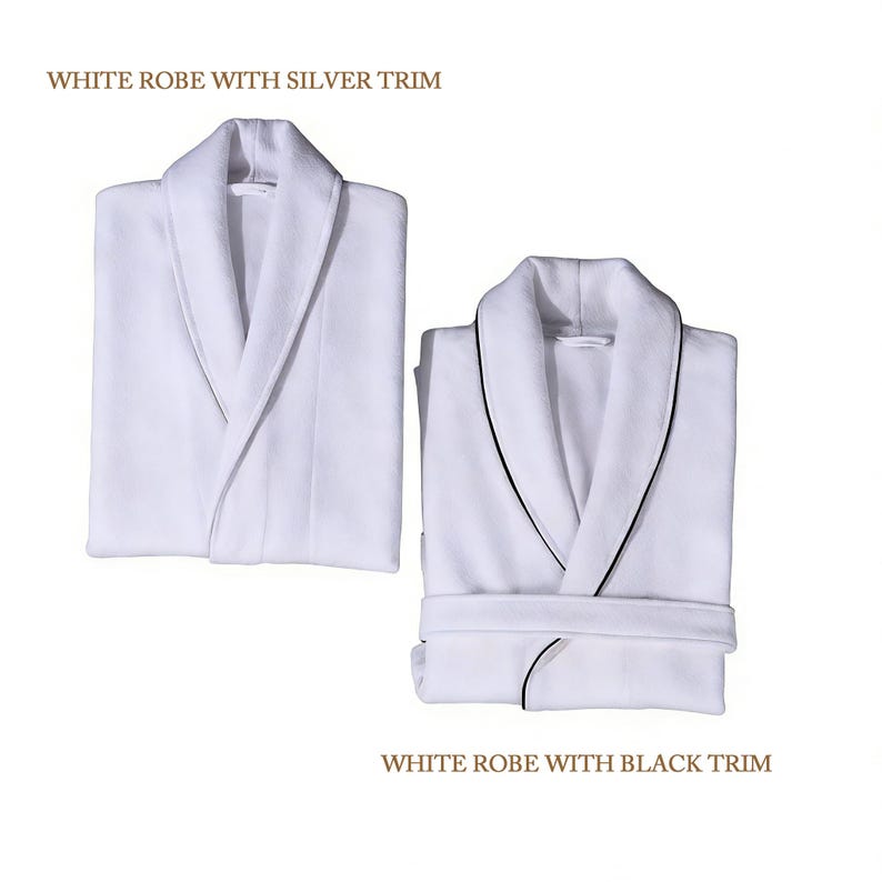 Puede incluir: Dos albornoces blancos con cuello chal. Uno tiene ribete plateado, el otro negro. El texto "WHITE ROBE WITH SILVER TRIM" y "WHITE ROBE WITH BLACK TRIM" se muestra encima y debajo de los albornoces.