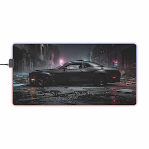 May include: A black sports car is the focal point of this image, set against a moody, urban backdrop. The car is parked on a wet street, with reflections of neon lights adding to the atmosphere. The image is printed on a rectangular mouse pad with a glowing edge.