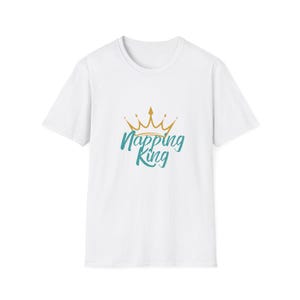 Könnte beinhalten: Weißes T-Shirt mit einem goldenen Kronen-Design und dem türkisfarbenen Text "Napping King". Das Rundhals-T-Shirt ist aus einem weichen Material gefertigt. Die Grafik ist mittig auf der Vorderseite platziert.