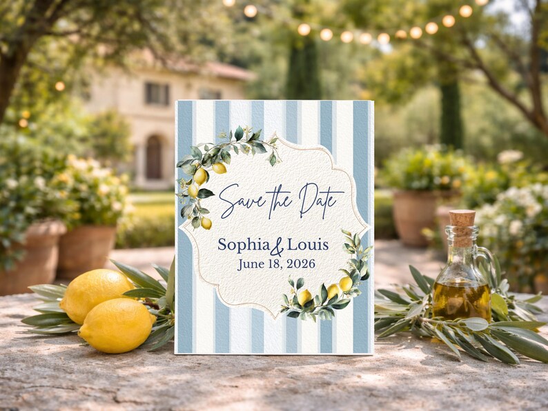 May include: A Save the Date card with blue and white stripes, featuring a floral lemon design and the names Sophia & Louis, with the date June 18, 2026. Two lemons and a bottle of olive oil are in the foreground.