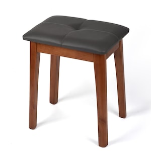May include: dark gray padded seat stool with a tufted design. The seat is supported by four wooden legs in a warm brown tone. The stool is a simple, functional piece of furniture.