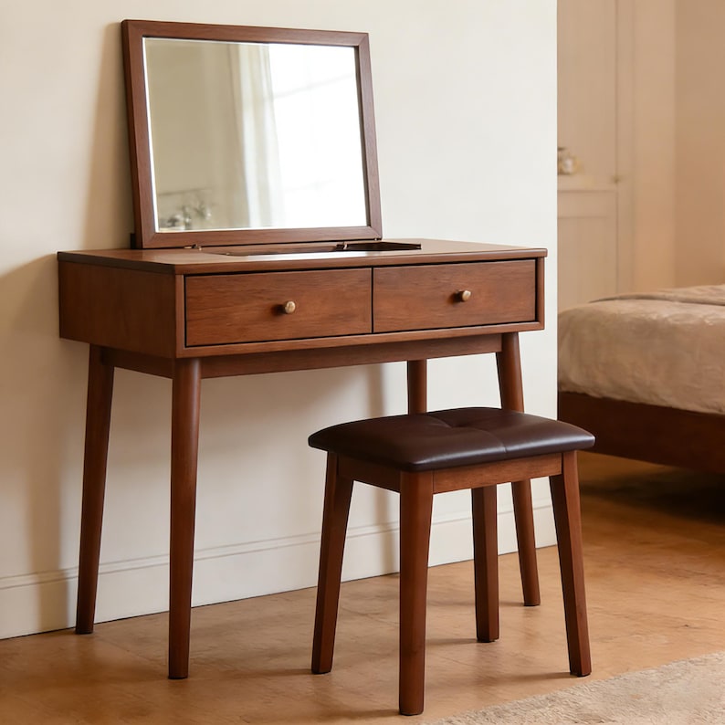 May include: A mid-century modern vanity stool. The stool has a brown leather seat and solid wood legs
