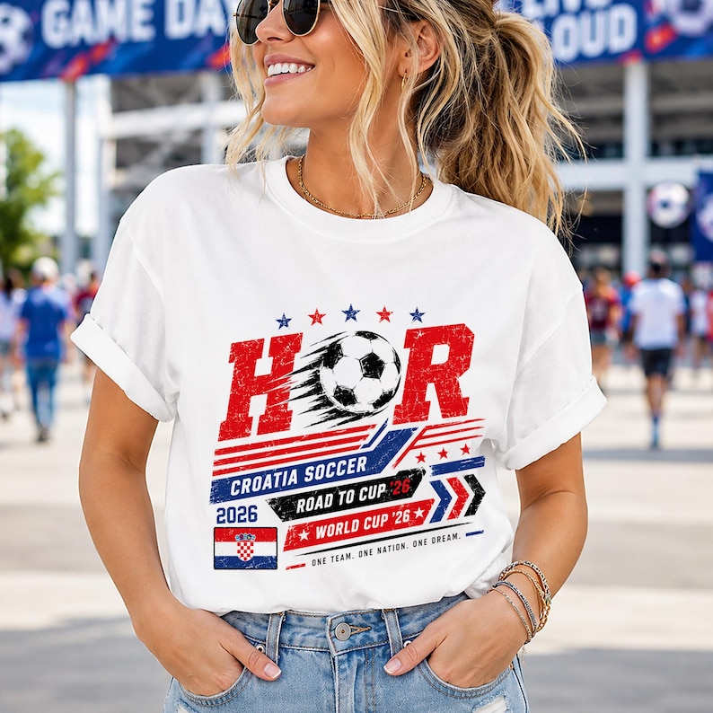 Może przedstawiać: Biały t-shirt z kr&oacute;tkim rękawem z grafiką przedstawiającą napis HOR, piłkę nożną, flagę Chorwacji oraz słowa Croatia Soccer Road to Cup 2026 World Cup 26 One Team, One Nation, One Dream w czerwonych, białych i niebieskich postarzanych literach.