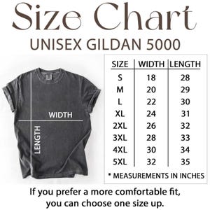 Może przedstawiać: Tabela rozmiar&oacute;w koszulki Gildan 5000 z ciemnoszarym t-shirtem oraz liniami szerokości i długości. Tabela zawiera rozmiary od S do 5XL z wymiarami w calach. Tekst brzmi: Jeśli wolisz bardziej komfortowe dopasowanie, możesz wybrać rozmiar większy.