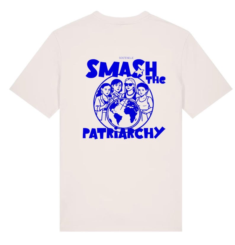 May include: Cream-colored t-shirt with a blue graphic on the back. The graphic features four women surrounding a globe, with the words "SMASH THE PATRIARCHY" in blue. The brand name "SOSTENELLE" is above the graphic.