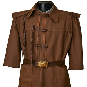 May include: A brown jacket with short sleeves, leather details, and wooden toggle fastenings. The jacket has a belt with a star-shaped buckle and braided embellishments. The jacket is displayed on a mannequin.