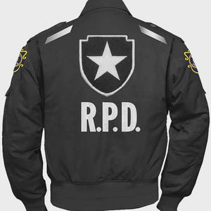 Może przedstawiać: Czarna kurtka bomberka z białymi literami "R.P.D.". Kurtka ma białą gwiazdę w tarczy na plecach i naszywki na ramionach. Kurtka ma prążkowany dół i mankiety.