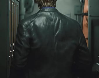 Puede incluir: Chaqueta de cuero negra con un diseño clásico. La chaqueta tiene cuello y cierre de cremallera. La persona lleva una camisa azul debajo. El fondo es un pasillo con taquillas.