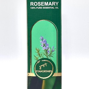 May include: A green box of rosemary essential oil. The box has the text "ROSEMARY 100% PURE ESSENTIAL OIL" and a graphic of a sprig of rosemary. The box also has the text "SYAM HOMES" and contains 30 ml of oil.