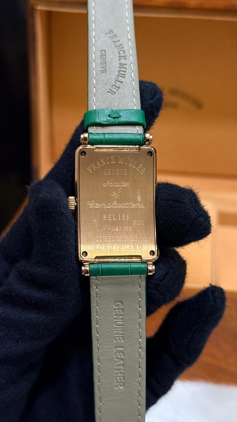 Op de afbeelding: Een gouden Franck Muller horloge met een rechthoekige wijzerplaat en een groene leren band. De wijzerplaat toont de merknaam en modeldetails. De band is groen en de woorden "Genuine Leather" zijn zichtbaar.
