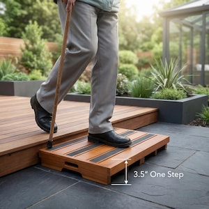 May include: A wooden step with black non-slip strips, labeled "3.5" One Step." The step is designed to assist with elevation changes. The person in the image is using a cane. The step is made of wood and is placed on a wooden deck.