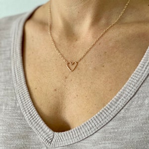 May include: A gold chain necklace with a delicate open heart pendant.