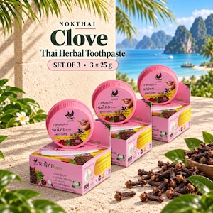 Könnte beinhalten: Ein Set aus drei Nokthai Clove Thai Herbal Zahnpasta-Dosen, je 25g, mit rosa runden Deckeln und passenden rosa Schachteln. Die Verpackung zeigt Text, ein Vogellogo und eine lächelnde Person. Getrocknete Gewürznelken liegen verstreut daneben.