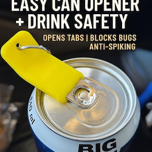 May include: A yellow can opener with a key ring, opening a can of Big beer. The can opener is designed to open tabs and block bugs. The can has "995 ml" printed on it. The text "EASY CAN OPENER + DRINK SAFETY" is at the top.