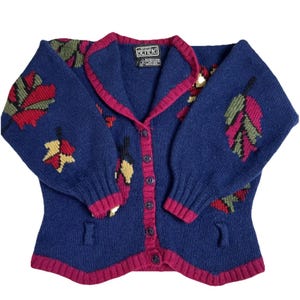 Könnte beinhalten: Marineblauer Cardigan mit bordeauxfarbenem Besatz und Blattmuster. Der Pullover hat eine Knopfleiste vorne, zwei Taschen und die Marke "BEREK" auf dem Etikett.