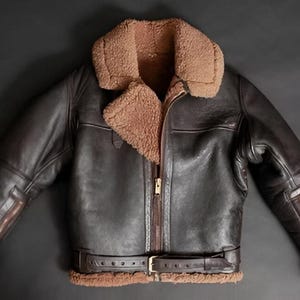 Puede incluir: Chaqueta de cuero marrón con cuello y forro de borrego. La chaqueta tiene cremallera frontal, cinturón en la cintura y mangas con cremallera. Un estilo clásico para climas fríos.