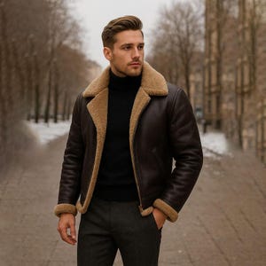 Puede incluir: Una chaqueta de cuero marrón oscuro con forro de borrego beige, cuello ancho con muescas y mangas largas con puños de borrego. La chaqueta se lleva sobre un suéter de cuello alto negro y pantalones gris oscuro, con cierre de cremallera.
