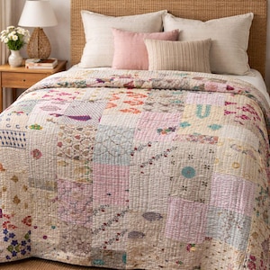 Könnte beinhalten: Ein Patchwork-Quilt mit verschiedenen floralen und geometrischen Mustern in Pastellfarben, darunter Rosa, Lavendel und Creme. Der Quilt liegt auf einem Bett mit mehreren Kissen und einem gewebten Kopfteil. Das Bett steht auf einem gewebten Teppich.
