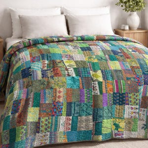 Peut inclure: Une courtepointe patchwork colorée dans les tons de vert, bleu, orange et violet recouvre un lit. La courtepointe est composée de divers carrés de tissu avec différents motifs. Le lit a des oreillers blancs et des tables de chevet en bois.