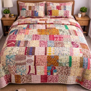 Può includere: Un quilt patchwork e due federe abbinate in una camera da letto. Il quilt presenta quadrati di tessuto in tonalità rosa, gialle e blu. Il letto è composto da una testiera in legno marrone e due comodini abbinati.