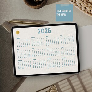 Puede incluir: Calendario digital para el año 2026 en una tableta. El calendario es de color beige claro con texto azul y un acento dorado. El texto "ETSY COLOR OF THE YEAR" está en la esquina superior derecha.