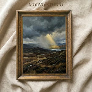 May include: A framed landscape painting with a gold-colored ornate frame. The artwork depicts a dramatic sky with dark clouds and a beam of sunlight shining down on a valley with a lake. The text "MORVO STUDIO" is at the top.