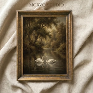 May include: A framed landscape painting featuring two white swans on a calm lake. The artwork is set in a forest with trees and a river, framed in a gold-colored wooden frame. The text "MORVO STUDIO" is at the top.