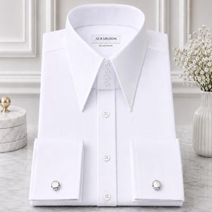 May include: A crisp white dress shirt with a wide collar and French cuffs. The shirt features the brand name "AURABLOOM" and "Royal Oxford" printed on the label. Silver cufflinks are visible on the cuffs. The shirt is neatly folded and presented.