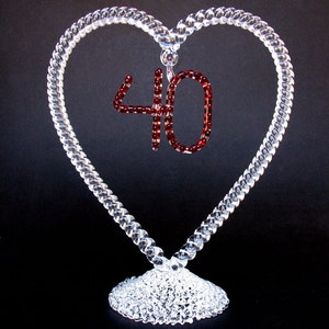 May include: A clear glass heart-shaped frame with a red rhinestone number 40 in the center. The frame is on a clear glass base.