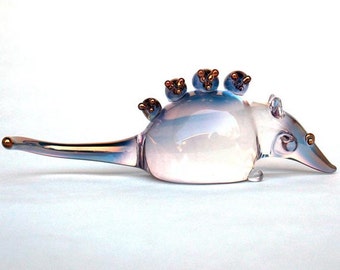 May include: A clear glass figurine of a mouse with four smaller mice on its back. The mice are all facing forward and have gold accents on their noses and eyes.