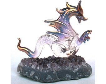 May include: A glass dragon figurine with iridescent wings and a tail, perched on a bed of amethyst crystals.
