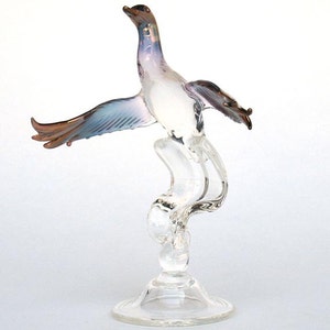 May include: A glass bird figurine with iridescent wings, perched on a swirling glass branch, with a clear glass base.