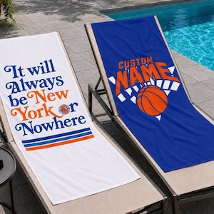 May include: Two rectangular beach towels draped over lounge chairs. One white towel features the blue and orange text It will Always be New York or Nowhere. The other blue towel displays an orange basketball graphic with the text CUSTOM NAME.