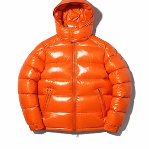 May include: Bright orange puffer jacket with a hood. The jacket has a glossy finish, a full-length zipper, and two zippered pockets. The puffy design is visible, and the jacket appears to be made of a water-resistant material.