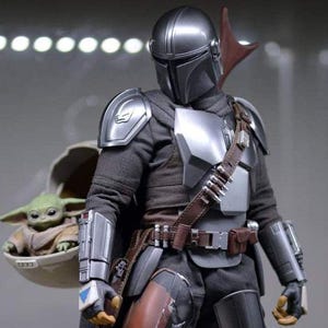Puede incluir: Figura de acci&oacute;n detallada de The Mandalorian con armadura plateada y negra, con cintur&oacute;n y capa de cuero marr&oacute;n. La figura lleva un peque&ntilde;o alien&iacute;gena verde en una c&aacute;psula flotante. La figura est&aacute; en una pose din&aacute;mica.
