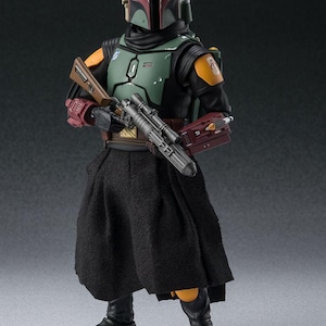 May include: A detailed action figure of Boba Fett from Star Wars. The figure is clad in a green, black, and orange armored suit, complete with a helmet and jetpack. It holds a blaster rifle and wears a black skirt-like garment. The figure stands on a neutral background.
