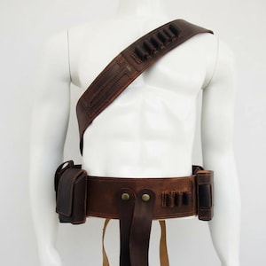 May include: A brown leather gun belt and shoulder holster set. The belt features multiple cartridge loops and two attached pouches. The shoulder strap also has cartridge loops. The set is displayed on a white mannequin.