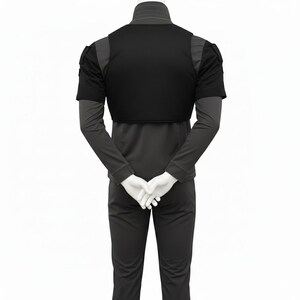May include: Black tactical vest with short sleeves and shoulder details. The vest is worn over a long-sleeved top and trousers. The mannequin's hands are clasped behind its back.