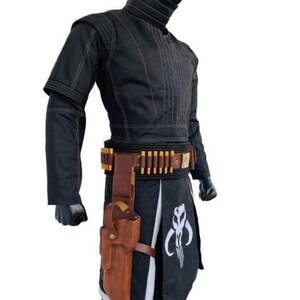 Puede incluir: Traje negro con capucha, cintur&oacute;n de cuero marr&oacute;n con detalles dorados y una funda. El disfraz incluye una falda negra con un emblema blanco. El atuendo est&aacute; dise&ntilde;ado con costuras detalladas.