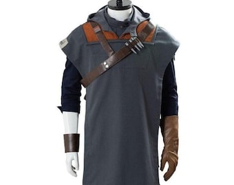 May include: A gray hooded tunic with brown leather accents and a shoulder strap, part of a costume. The costume includes a dark blue long-sleeved shirt, brown gloves, and a wrist cuff. The outfit is displayed on a mannequin.
