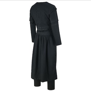 May include: A black outfit consisting of a long-sleeved top with shoulder detailing, a long skirt, and leggings. The outfit is made of a dark fabric and has a simple, elegant design. The skirt is pleated at the waist.