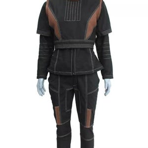 Puede incluir: Traje negro con detalles marrones y costuras blancas. El conjunto incluye una chaqueta con cuello alto y un pantal&oacute;n a juego. La chaqueta tiene un dise&ntilde;o &uacute;nico con paneles marrones en los hombros y el pecho. Los pantalones tienen parches marrones en las rodillas.