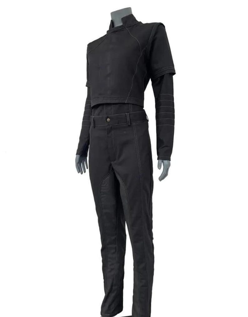 May include: A black two-piece outfit. The cropped jacket has short sleeves and long sleeves, with visible stitching. The matching trousers have a belt and a straight leg. The jacket has a high collar.