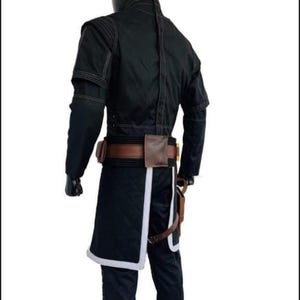 Puede incluir: Traje negro con cintur&oacute;n y bolsillos marrones. El traje presenta una chaqueta larga con ribete blanco y un pantal&oacute;n a juego. La chaqueta tiene cuello alto y mangas largas. El traje se exhibe en un maniqu&iacute;.