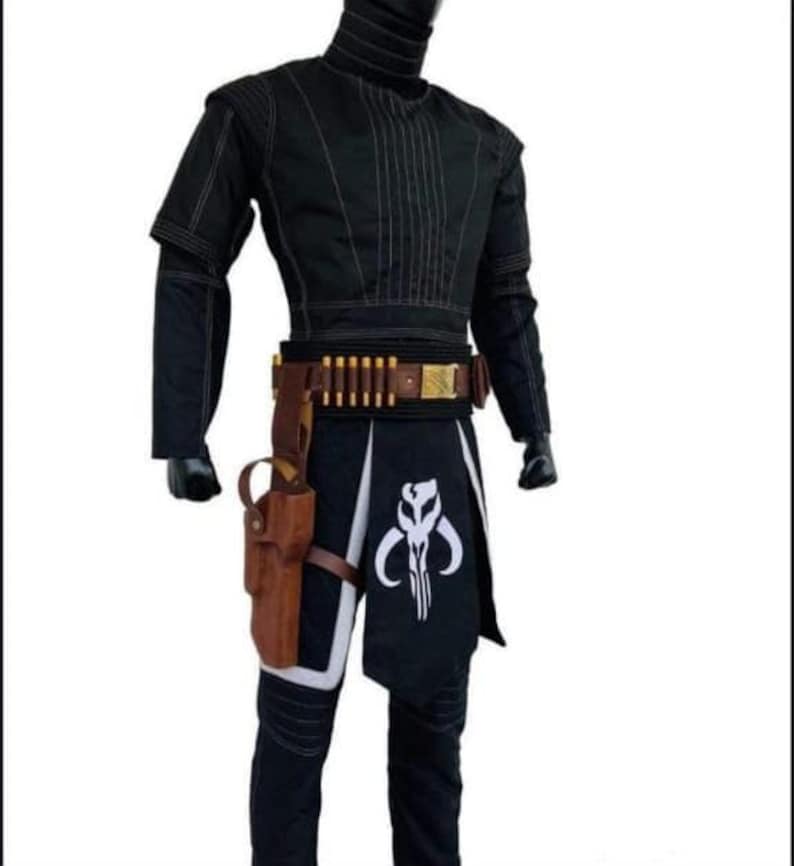 Puede incluir: Traje negro con costuras blancas, con cuello alto y mangas cortas. El atuendo incluye un cintur&oacute;n marr&oacute;n con porta balas, una funda y una falda negra con un emblema blanco. Un disfraz de cosplay.