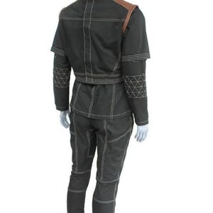 Puede incluir: Un conjunto de dos piezas verde oscuro con detalles de costura blancos. La chaqueta tiene detalles marrones en los hombros y cuello mandar&iacute;n. Los pantalones son ajustados. El conjunto se exhibe en un maniqu&iacute;.