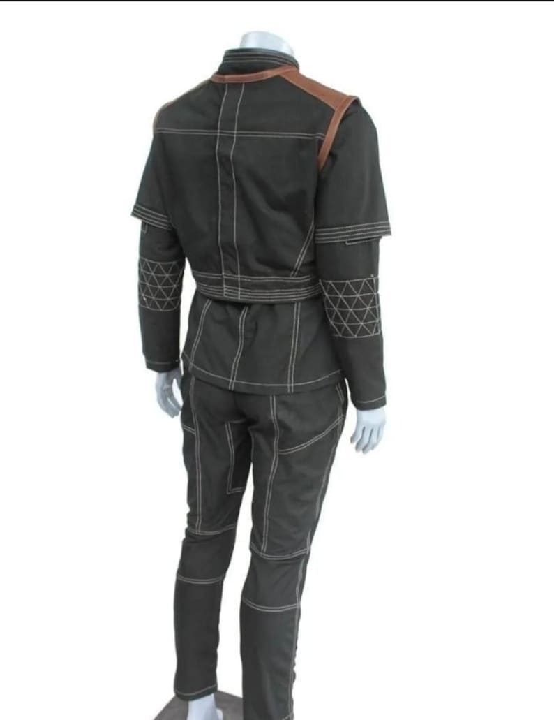 Puede incluir: Un conjunto de dos piezas verde oscuro con detalles de costura blancos. La chaqueta tiene detalles marrones en los hombros y cuello mandar&iacute;n. Los pantalones son ajustados. El conjunto se exhibe en un maniqu&iacute;.