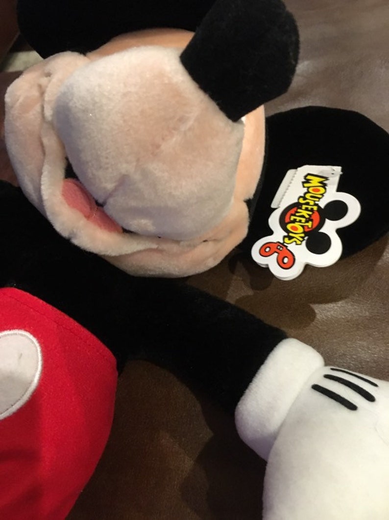 May include: A black and red plush Mickey Mouse toy with a white tag that says "Mouseketoys".