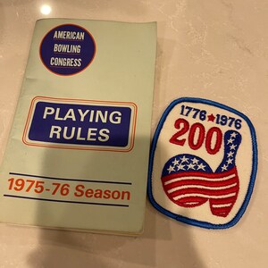 May include: A vintage American Bowling Congress playing rules booklet from the 1975-76 season, next to a blue, white, and red embroidered patch with the text "1776-1976 200" and a bowling pin graphic.