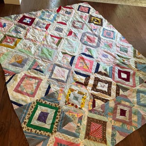 May include: A patchwork quilt with a variety of colorful fabrics and patterns. The quilt is made up of squares and rectangles, and the colors include red, blue, green, yellow, and pink.